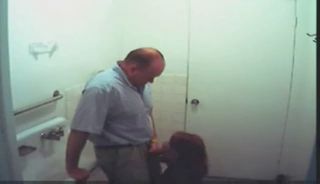 Een jonge roodharige slet zuigt een dikke man in een openbaar toilet